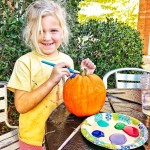 Smiling girl painting pumpkin